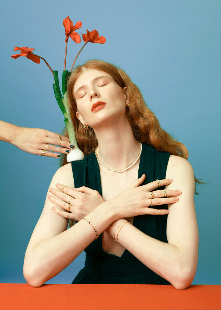 ginger woman posing with rings and red flowers